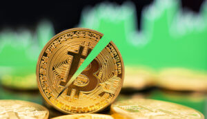 halbierte bitcoin münze die zwischen liegenden bitcoin münzen steht, im Hintergrund grüne Charts als Symbol für einen Bitcoin-Kurs-Anstieg nach dem Halving
