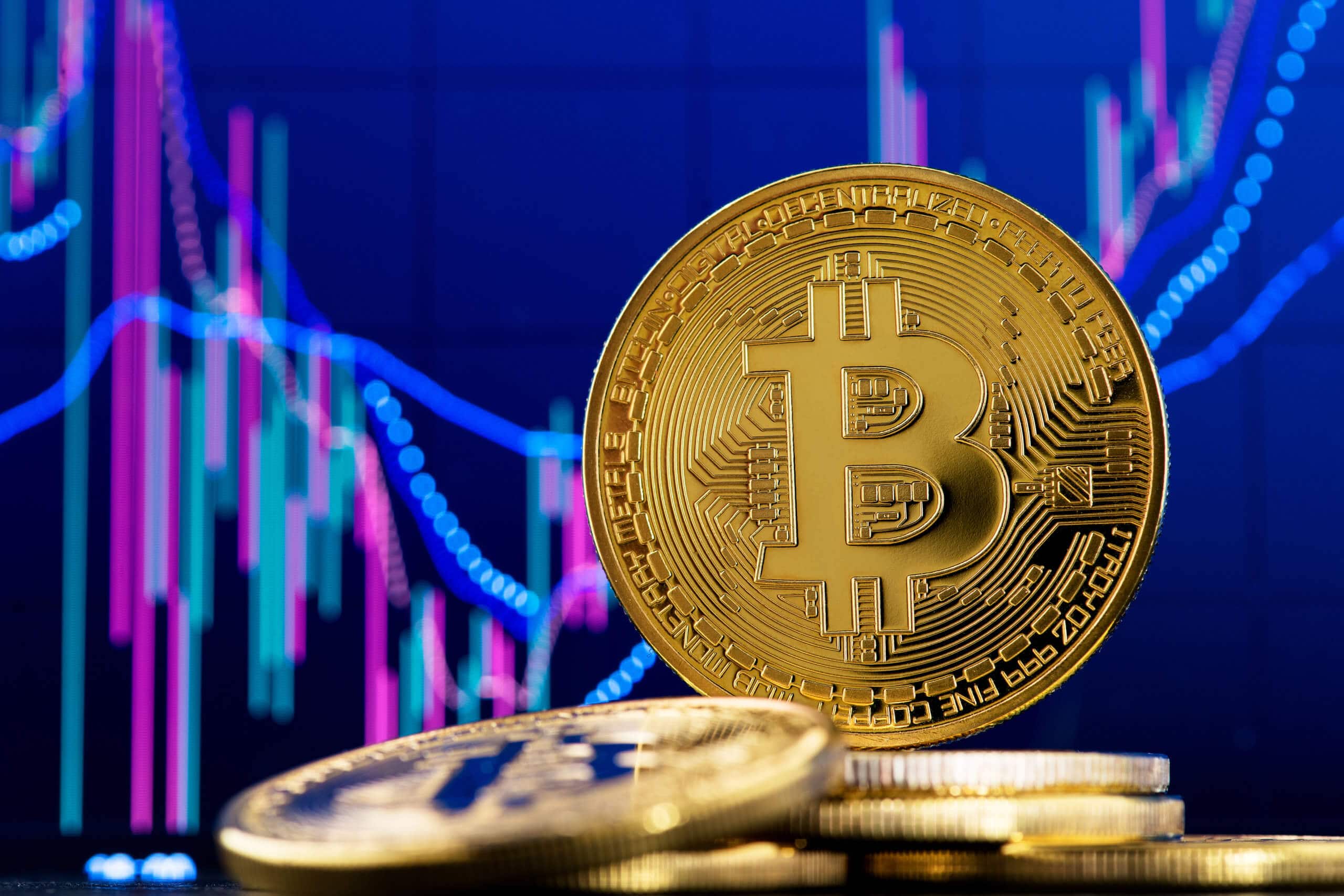 bitcoin-münze hinter liegenden bitcoin-münzen vor einer chart mit blauem hintergrund