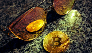 eine bitcoin-münze, die sich in einer sonnenbrille spiegelt