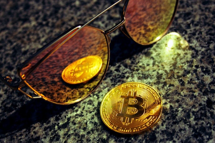 eine bitcoin-münze, die sich in einer sonnenbrille spiegelt