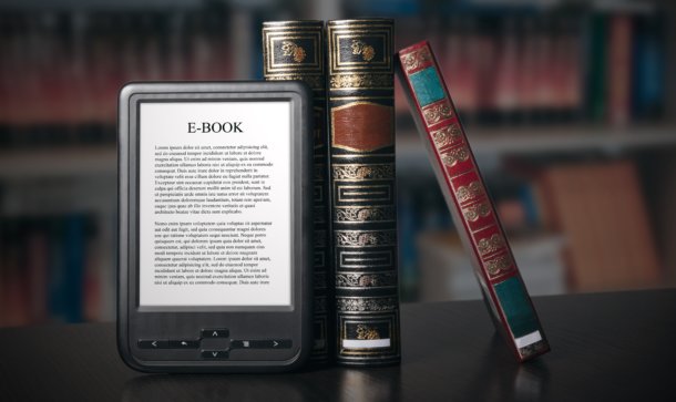 Alte Bücher und ein e-book stehen aufgestellt auf einem Tisch