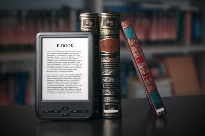 Alte Bücher und ein e-book stehen aufgestellt auf einem Tisch