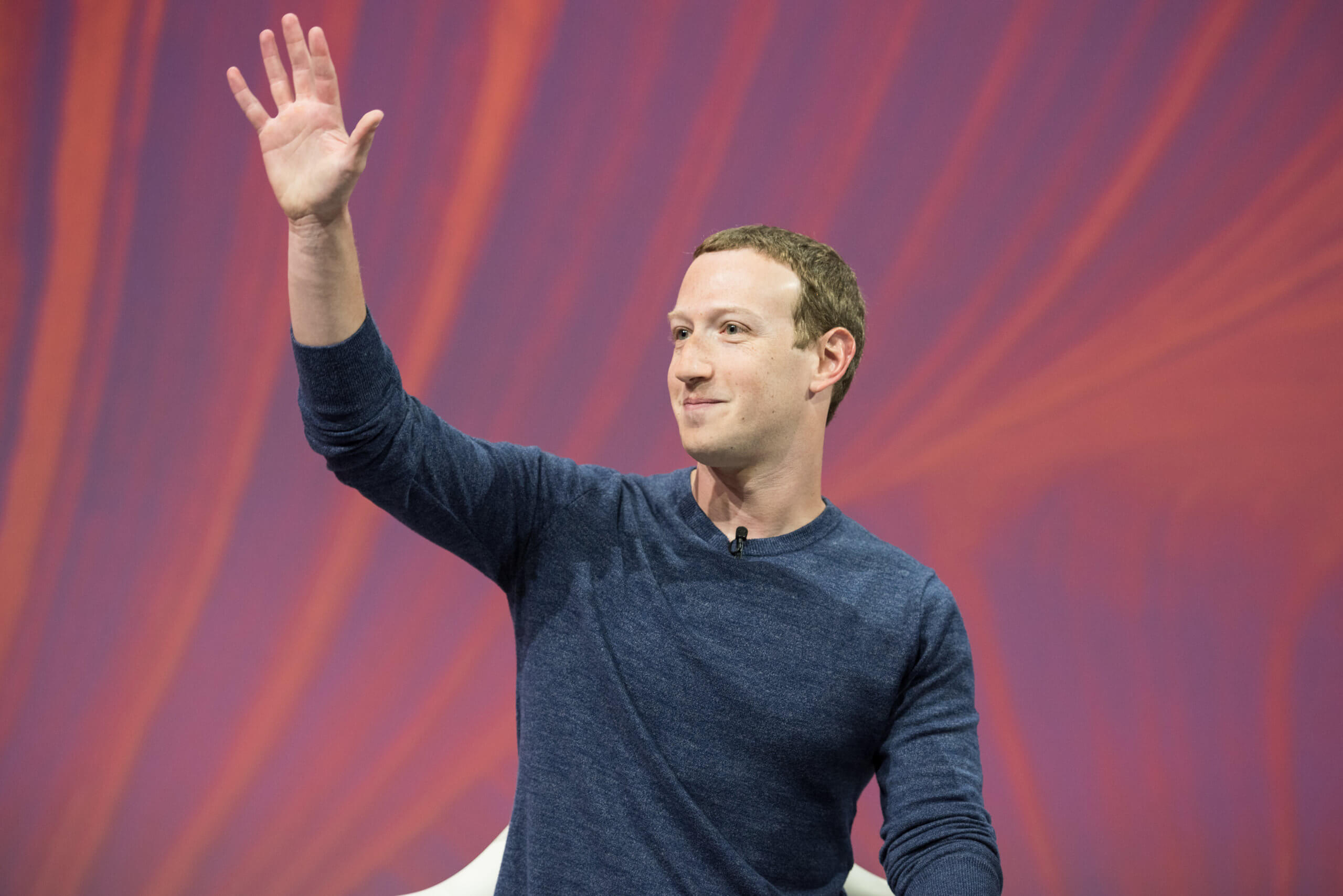 facebook chef markt zuckerberg winkt auf rotem hintergrund