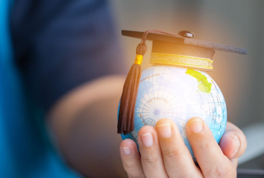 Bildungslücke Blockchain: Australische Universität und IBM kooperieren Frauenhand hält kleinen Globus mit Doktormütze