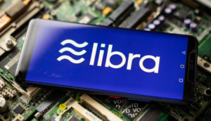 das libra-symbol auf einem smartphone, das auf einem elektronischen technologie-hintergrund liegt