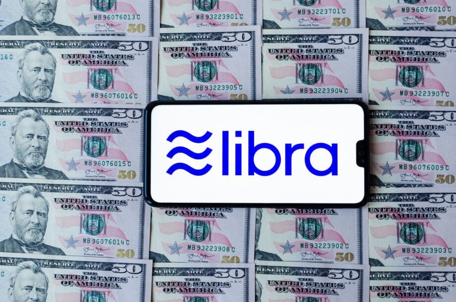 Libra 2.0 – Änderungen und Implikationen des „Facebook Coin“ Smartphone mit Libra-Logo auf druckfrischen Dollar-Noten