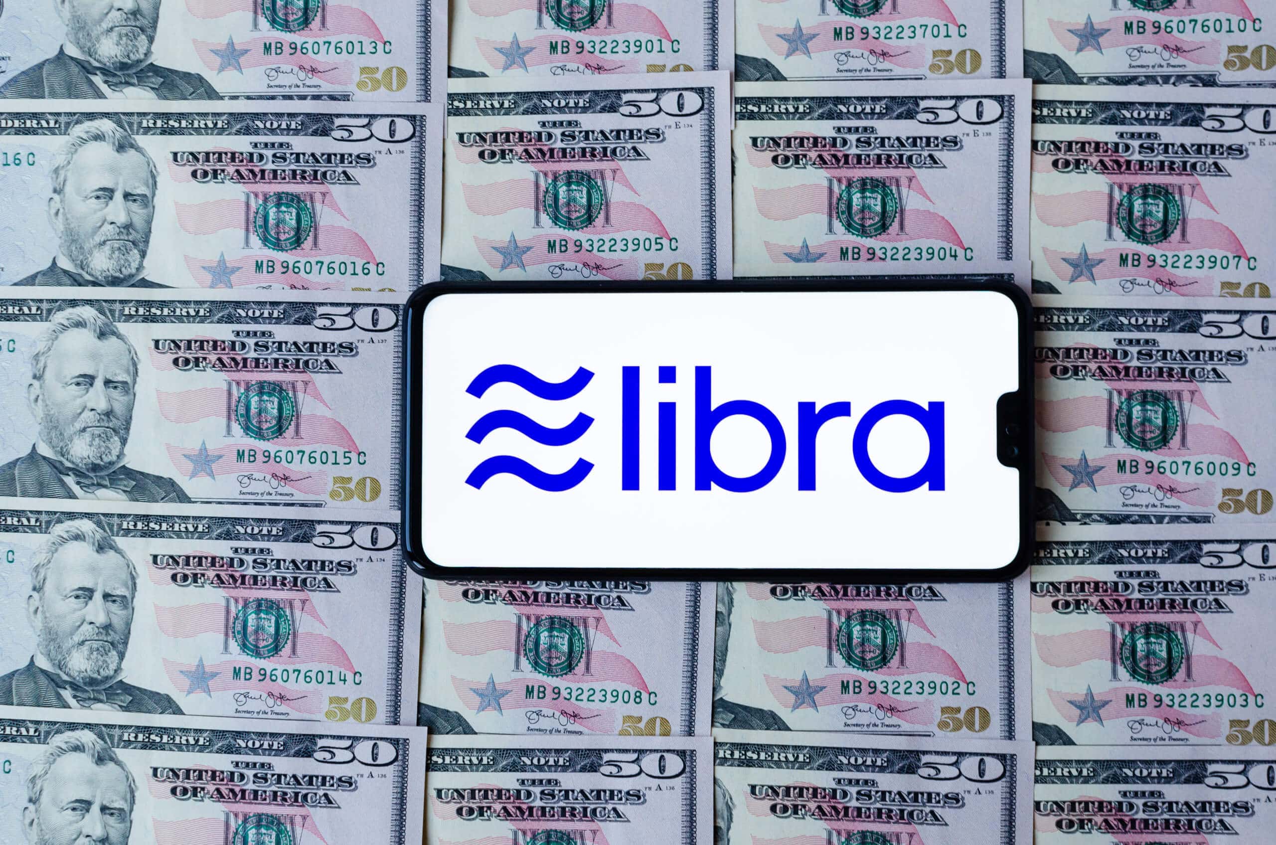 Smartphone mit Libra-Logo auf druckfrischen Dollar-Noten