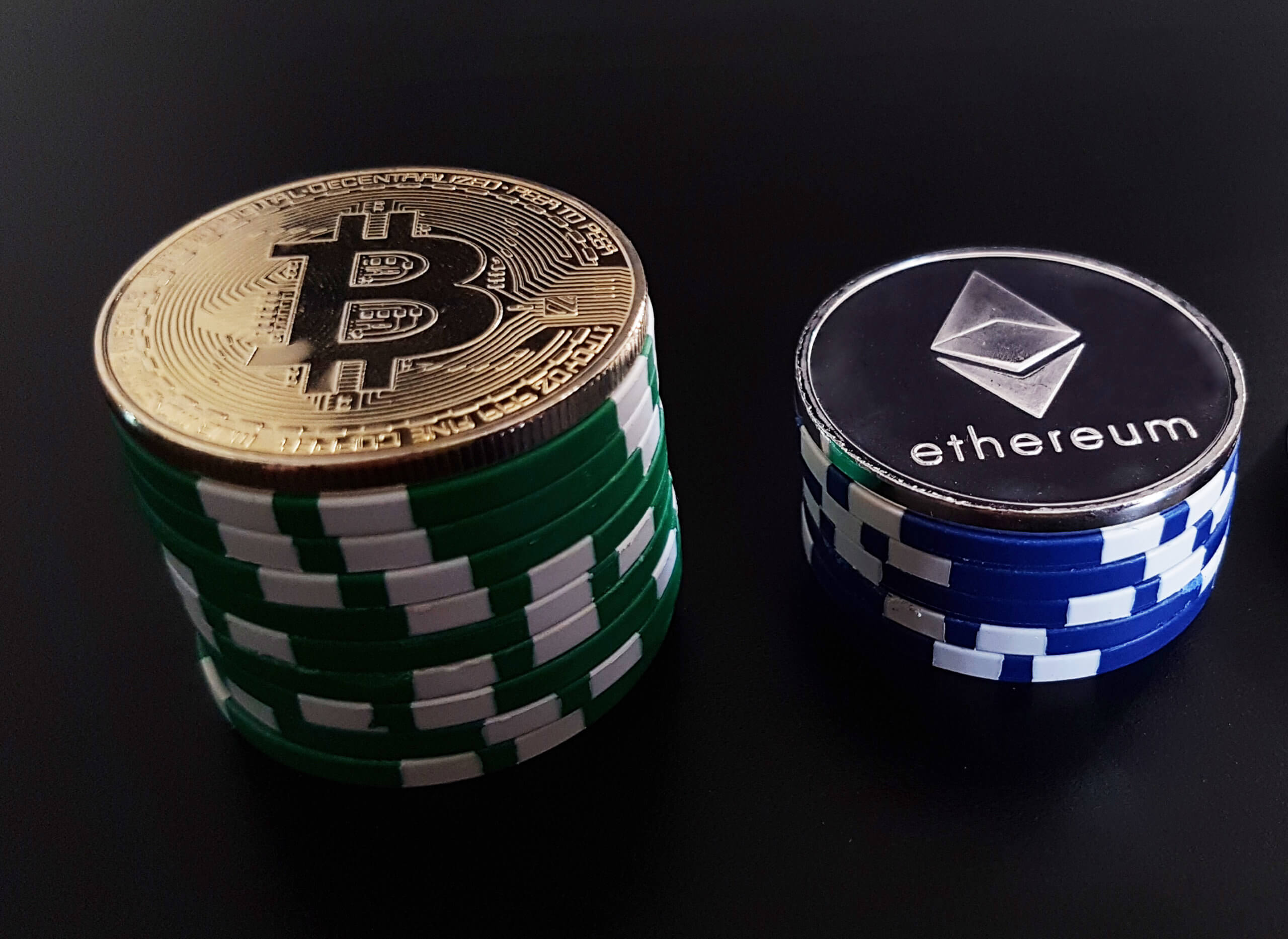 Zwei Stapel mit Pokerchips, links von Bitcoin, rechts von Ethereum-Münze gekrönt