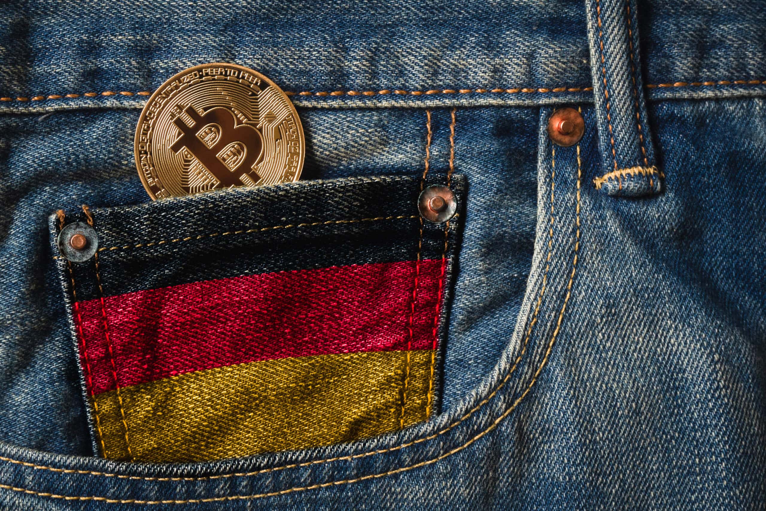 Bitcoin-Münze in schwarz-rot-gold-gefärbter Uhrentasche einer Jeans