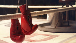 Ein Paar Boxhandschuhe hängt auf den Seilen eines Boxrings