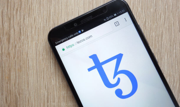 Tezos Foundation stärkt Governance und besetzt Leitungsfunktion Das Logo von Tezos auf einem Smartphone abgebildet