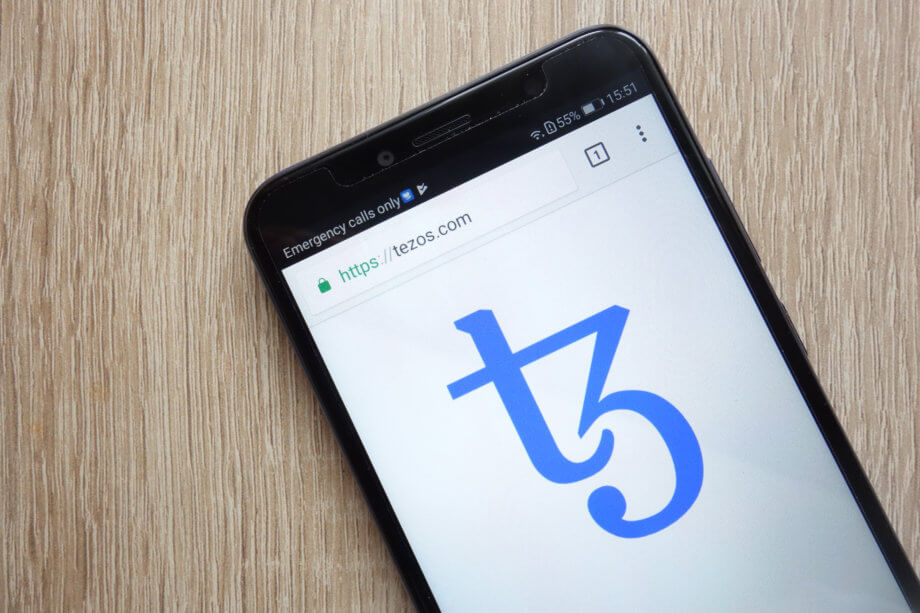 Tezos Foundation stärkt Governance und besetzt Leitungsfunktion Das Logo von Tezos auf einem Smartphone abgebildet