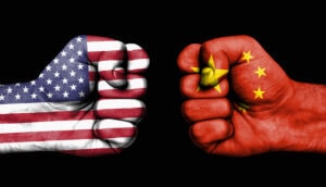 zwei fäuste, die auf einander zukommen, eine gefärbt mit der flagge der usa, die andere mit der flagge von china