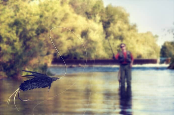 ein angler, der einen fisch aus dem wasser zieht