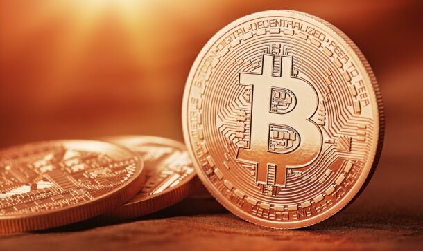 bitcoin-münze-steht-neben-liegenden-bitcoin-münzen