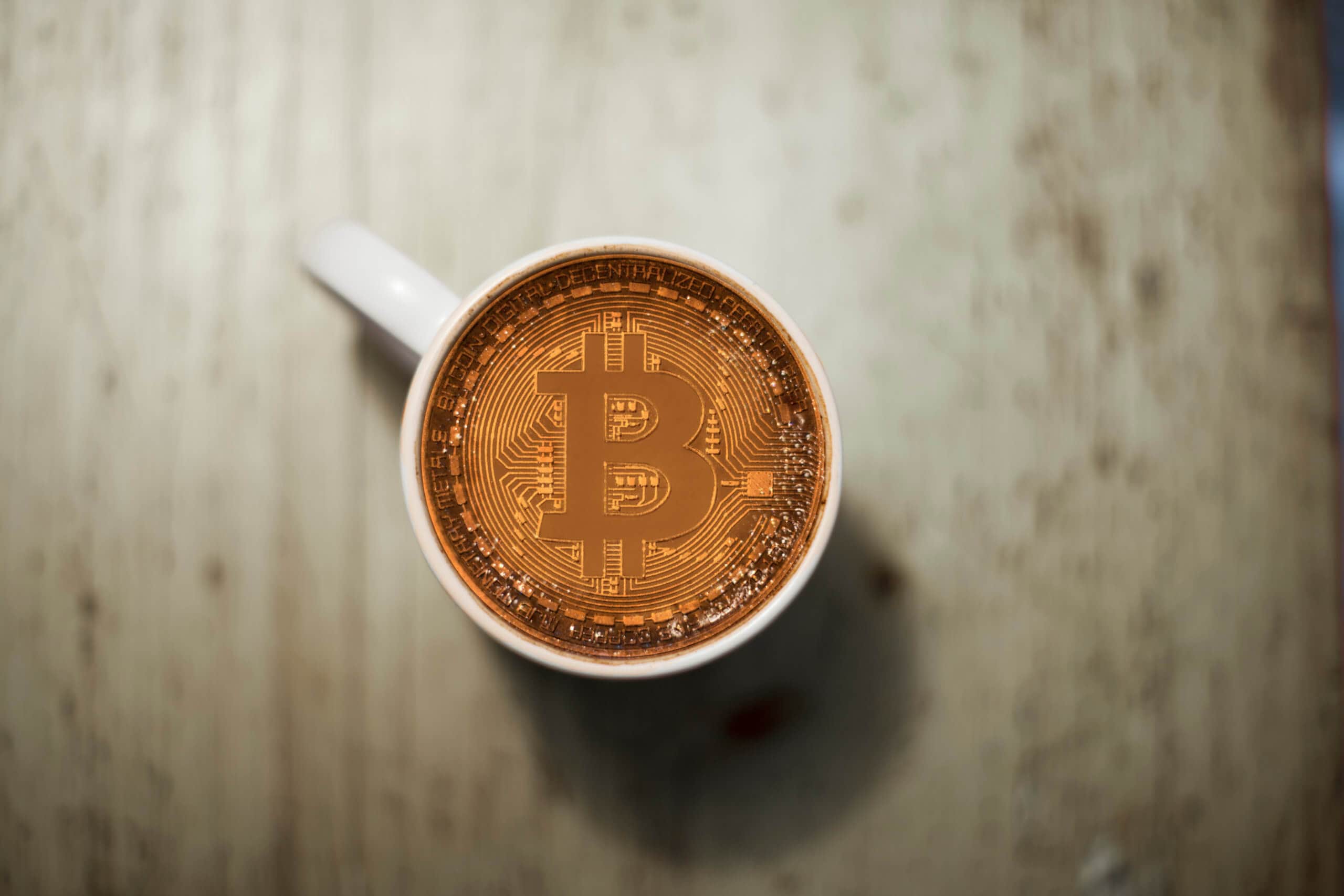 eine bitcoin-münze in einer kaffetasse