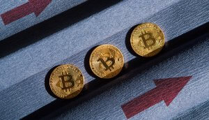 drei goldene bitcoin-münzen, daneben zwei rote pfeile, die nach rechts oben zeigen