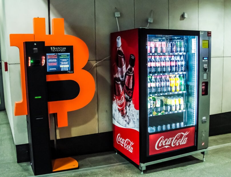 Coca-Cola-Automaten in Down Under unterstützen bald Bitcoin (BTC) Ein Bitcoin-Automat steht neben einem Coca-Cola-Automat