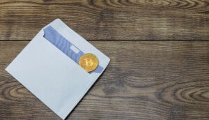 briefumschlag-mit-bitcoin-münze-auf-einem-holztisch