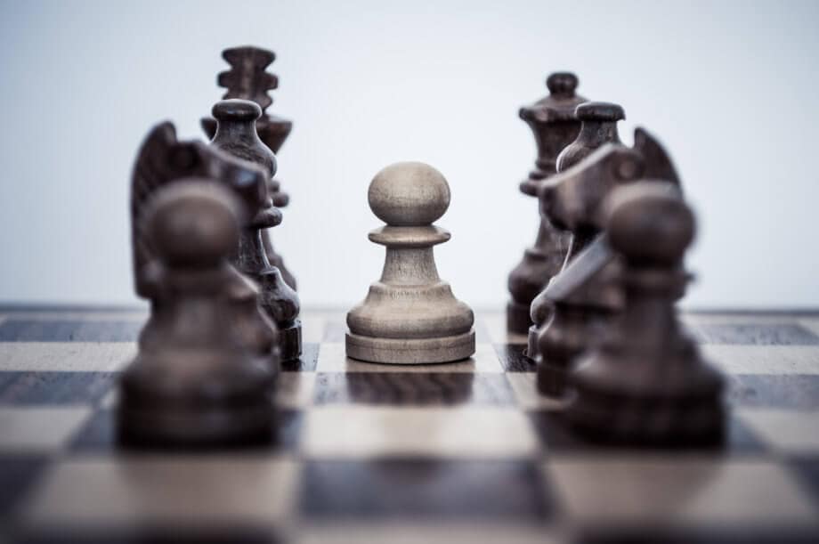 Die Derivatisierung von Bitcoin – Ein Eingeständnis an institutionelle Investoren? Auf einem Schachbrett ist ein Bauer von anderen Spielfiguren umzingelt, die institutionelle Investoren darstellen sollen.