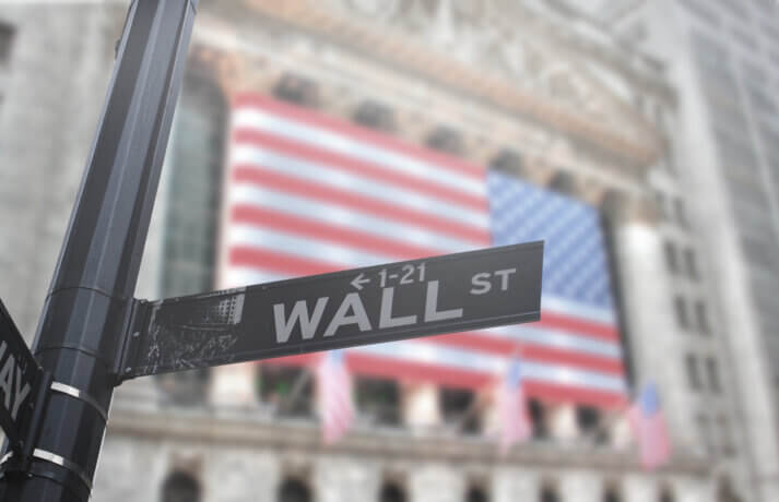 ein straßenschild mit der aufschrift wall st, im hintergrund eine amerikanische Flagge