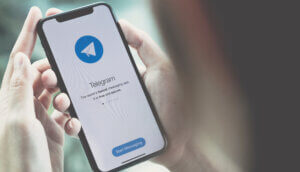 die telegram app auf einem smartphone, das von zwei händen gehalten wird