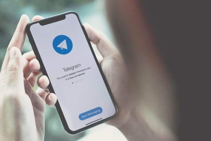 die telegram app auf einem smartphone, das von zwei händen gehalten wird