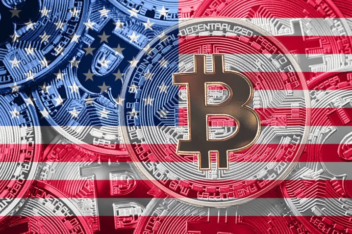 Ein mit der amerikanischen Flagge verschmolzenes Bitcoin-Symbol ruht vor einem Hintergrund aus gestapelten Bitcoin-Münzen und verkörpert die dynamische Schnittstelle zwischen Kryptowährung und den USA.