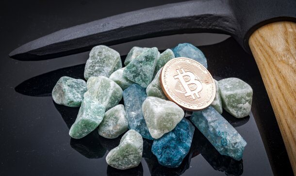 Bitcoin Mining: 1 BTC kostet durchschnittlich 5.000 US-Dollar Steine und Bitcoin-Münze neben Spitzhacke