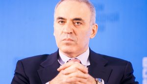 Kasparov-sitzt-vor-einem-blauen-hintergrund