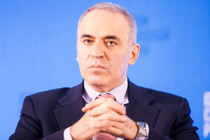 Kasparov-sitzt-vor-einem-blauen-hintergrund