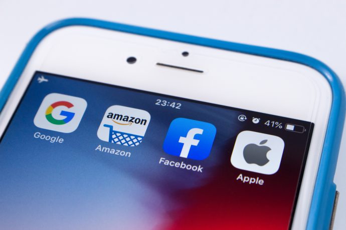 Die Symbole der Big Four: Google, Facebook, Amazon Apple auf einem smartphone als antithese zum bitcoin-system