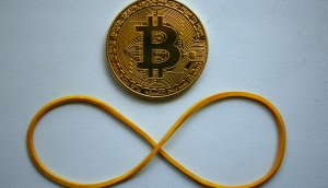 Bitcoin Münze mit Gummi, das zu einer liegenden Acht geformt wurde