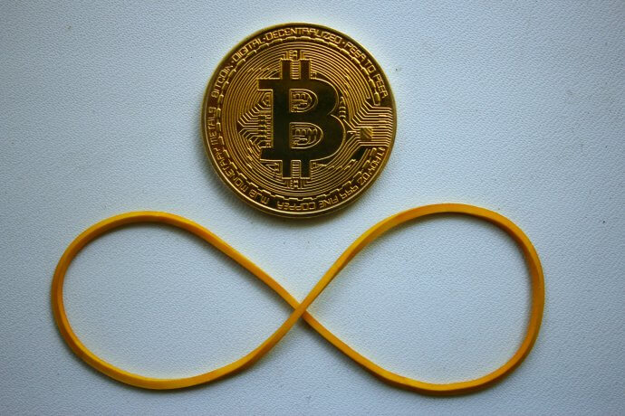 Bitcoin Münze mit Gummi, das zu einer liegenden Acht geformt wurde