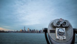 ein fernglas, das richtung stadt über das wasser schaut