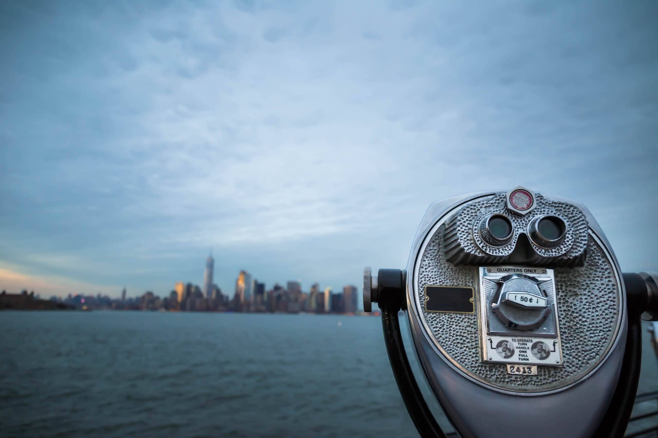 ein fernglas, das richtung stadt über das wasser schaut