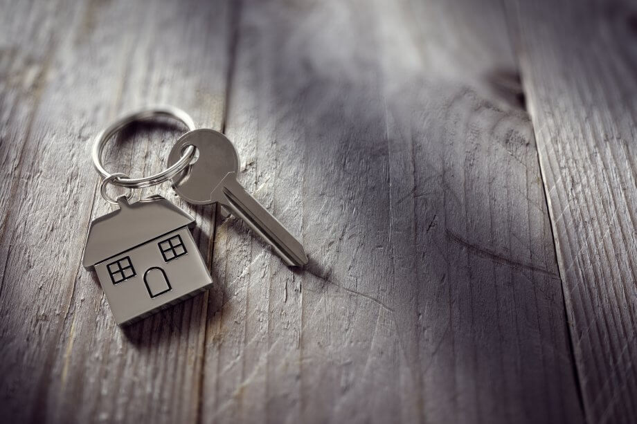 Finexity startet Plattform für Tippgeber ein schlüssel mit einem haus als anhänger auf grauem holzuntergrund