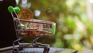 close up toy shopping cart with bitcoin on notebook,