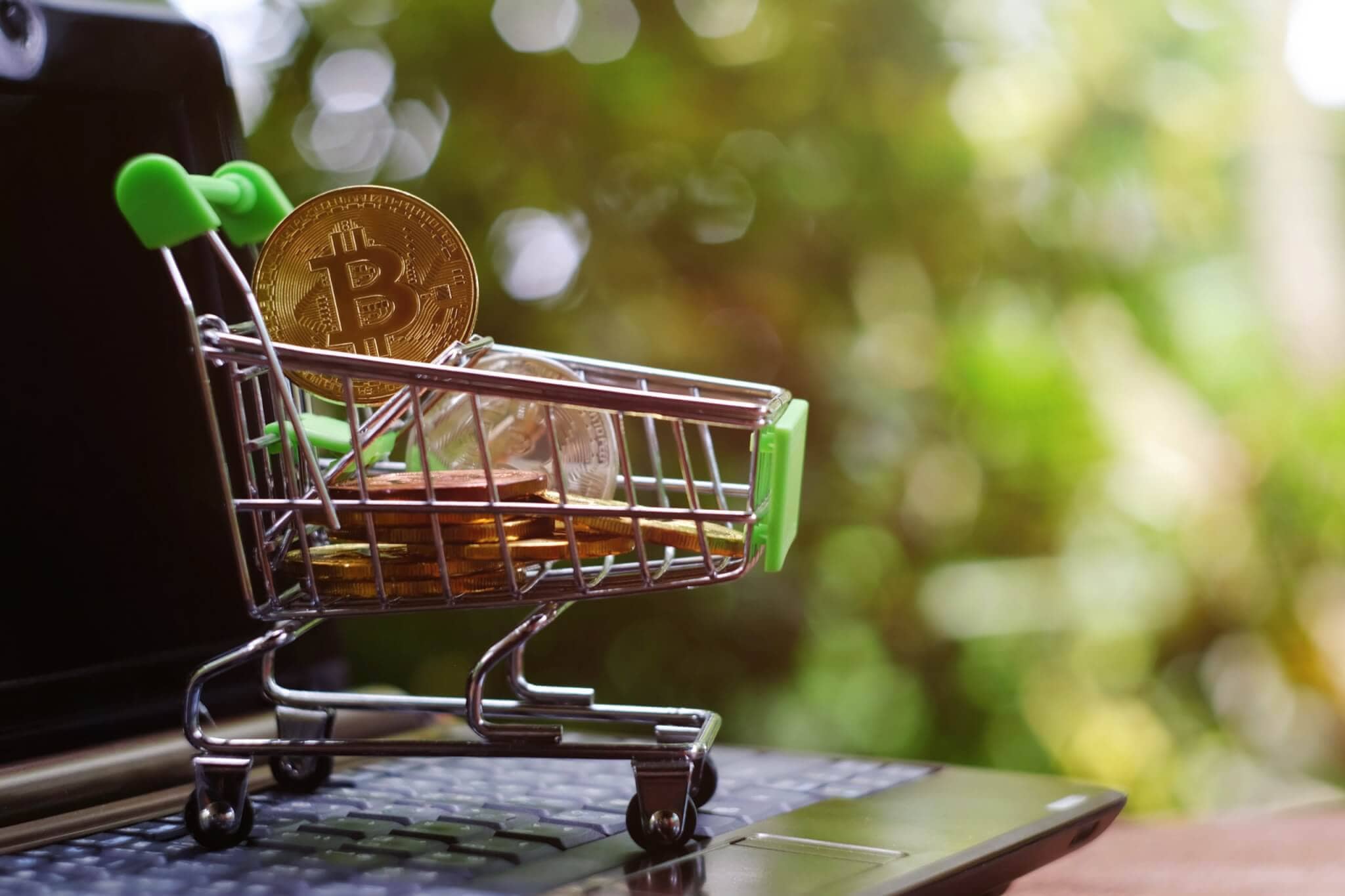 close up toy shopping cart with bitcoin on notebook,