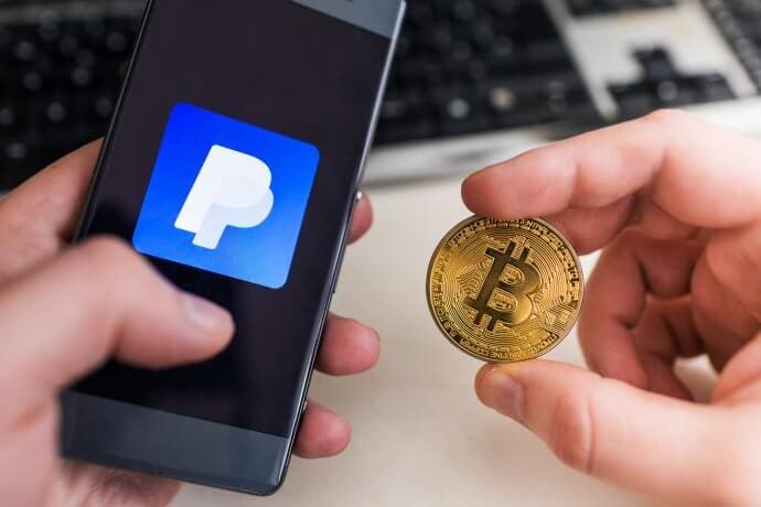 Smartphone mit PayPal-Logo, daneben eine Bitcoin-Münze