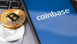 Bitcoin- und Ethereum-Münzen neben Smartphone mit Coinbase-Logo auf dem Bildschirm