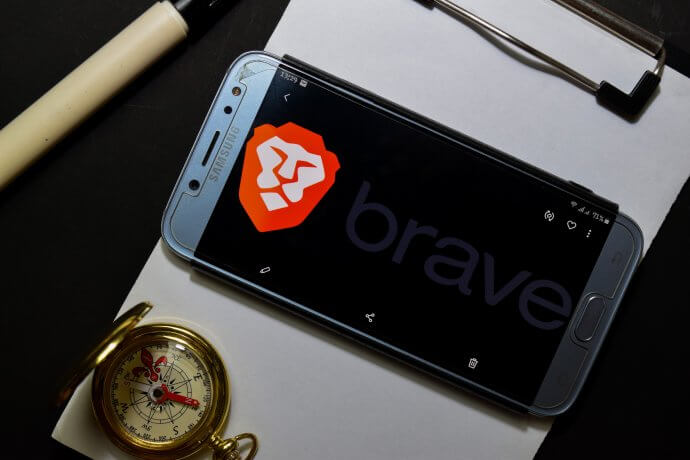 Smartphone auf Klemmbrett mit Kompass, das Display ziert das Logo des Brave Browser