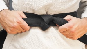 mensch-zieht-schwarzen-gürtel-zu