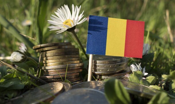 Rumänien: Mit EU-Gesetz auf dem Weg zur Krypto-Regulierung Romanian flag with stack of money coins with grass and flowers