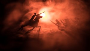 Weltkriegsoffizier (oder Krieger) reiten auf dem Pferd mit einem Schwert, das bereit ist zu kämpfen, und Soldaten auf dunkelnebelfarbenem Hintergrund. Schlachtfeld von Kampfsoldaten. Selektiver Fokus
