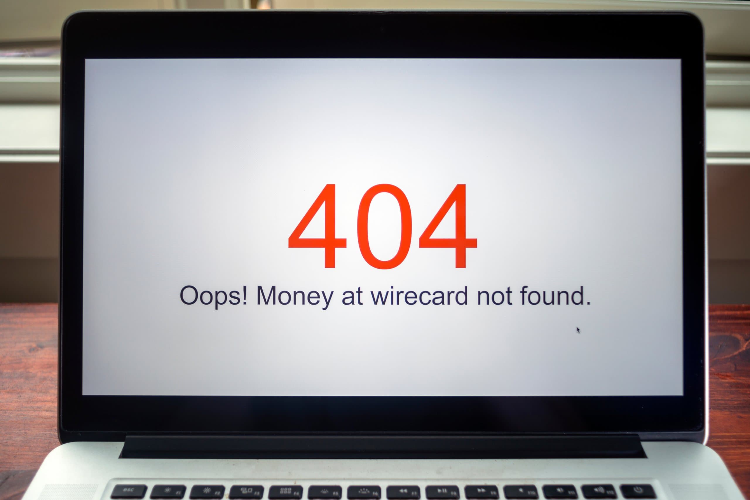 ein laptop, der die roten zahlen 404 zeigt und darunter in schwarzer schrift "oops" money at wirecard not found"