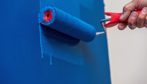 Mensch streicht Wand mit blauer Farbe