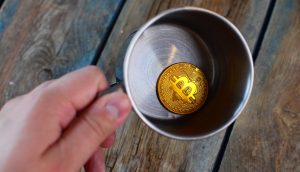 Bitcoin-Münze in einem leeren Metallbecher