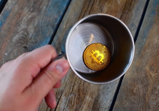 Bitcoin-Münze in einem leeren Metallbecher