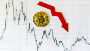 Bitcoin-Münze auf Chart mit rotem Pfeil der abwärts zeigt